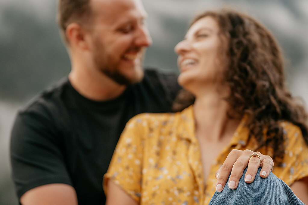 Couple sharing a joyful moment, focus on engagement ring.