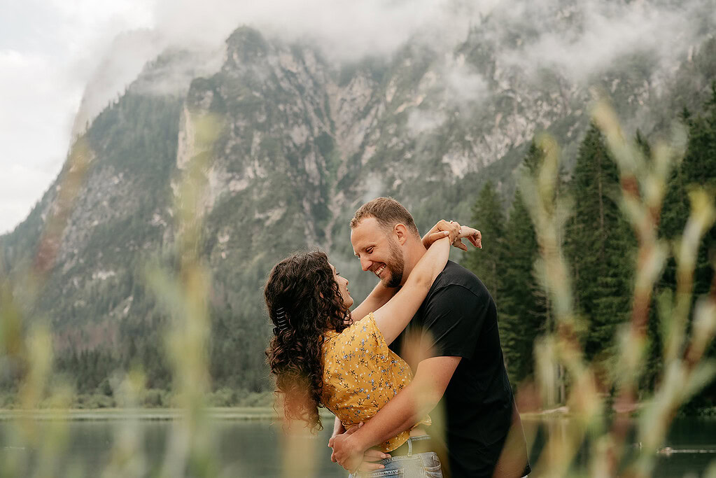 Couple embracing in front of misty mountain landscape.