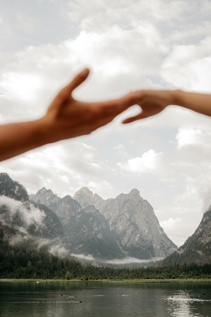 Hands reaching towards misty mountain landscape