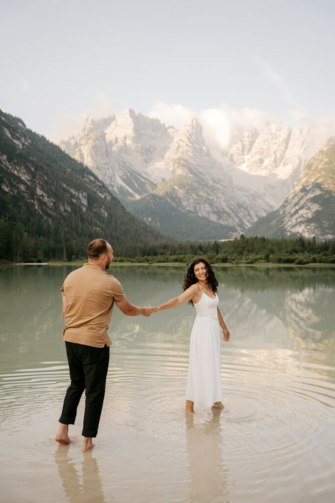 Couple holding hands by a mountain lake.