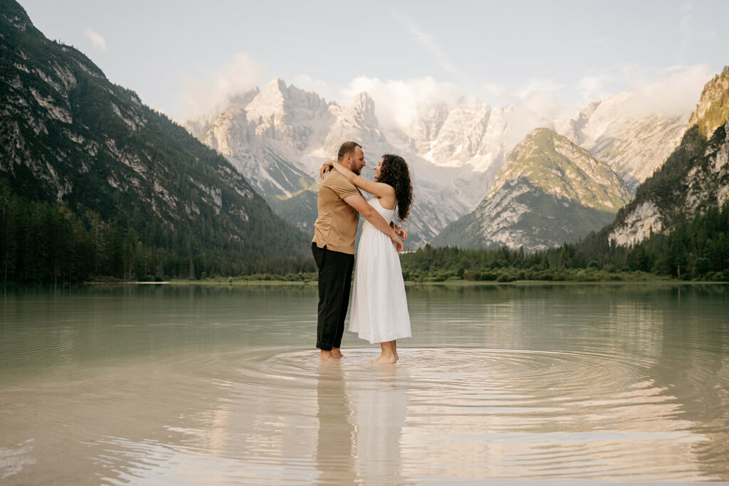 Couple embraces in mountain lake scenery.