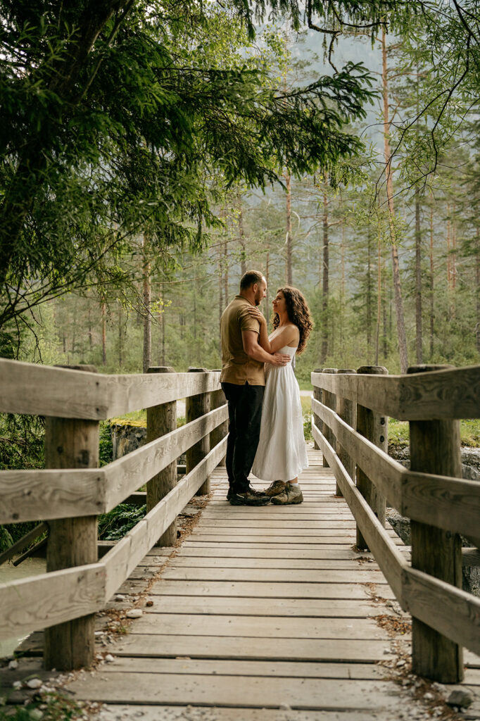 Couple embracing on a wooden bridge in forest.