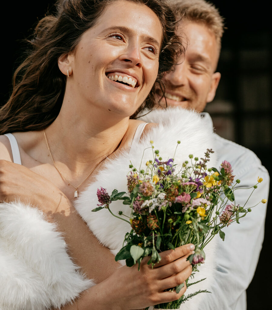 Smiling couple embracing with wildflower bouquet