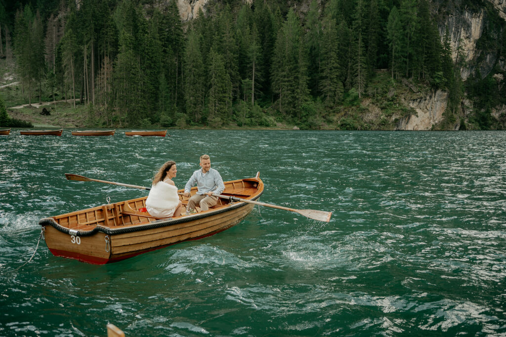 Couple rowing on a scenic lake surrounded by trees.