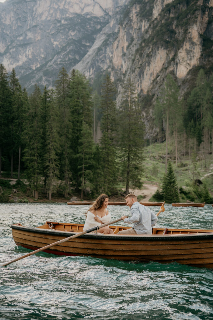 Couple rowing on scenic mountain lake.