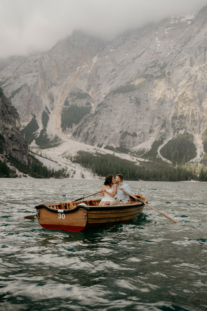 Couple kissing in a boat on mountain lake.