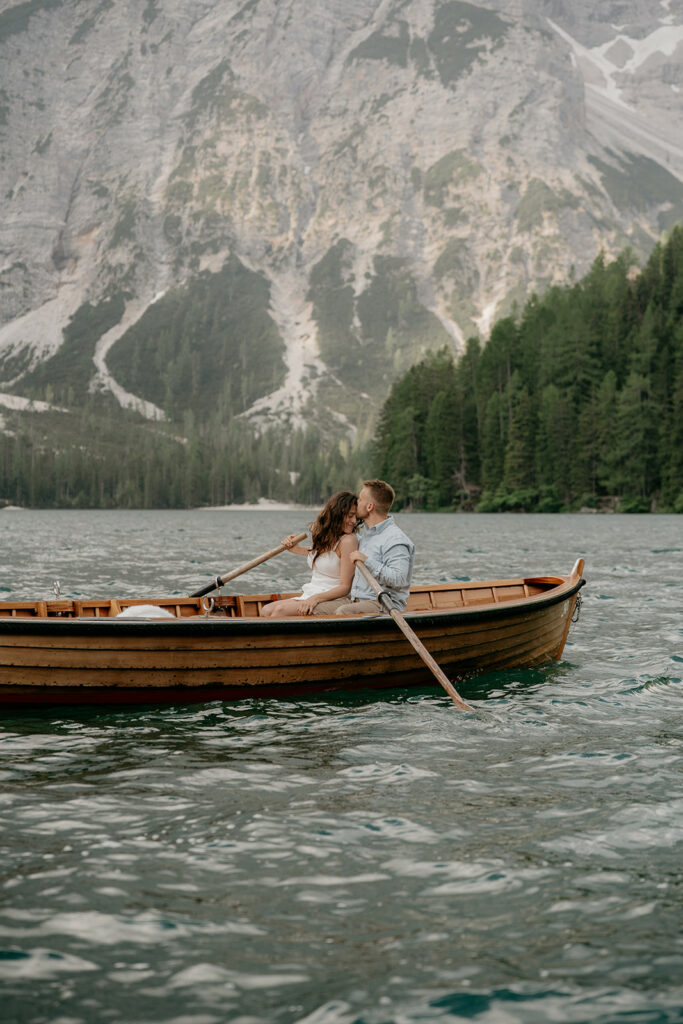 Couple kissing in wooden boat on mountain lake