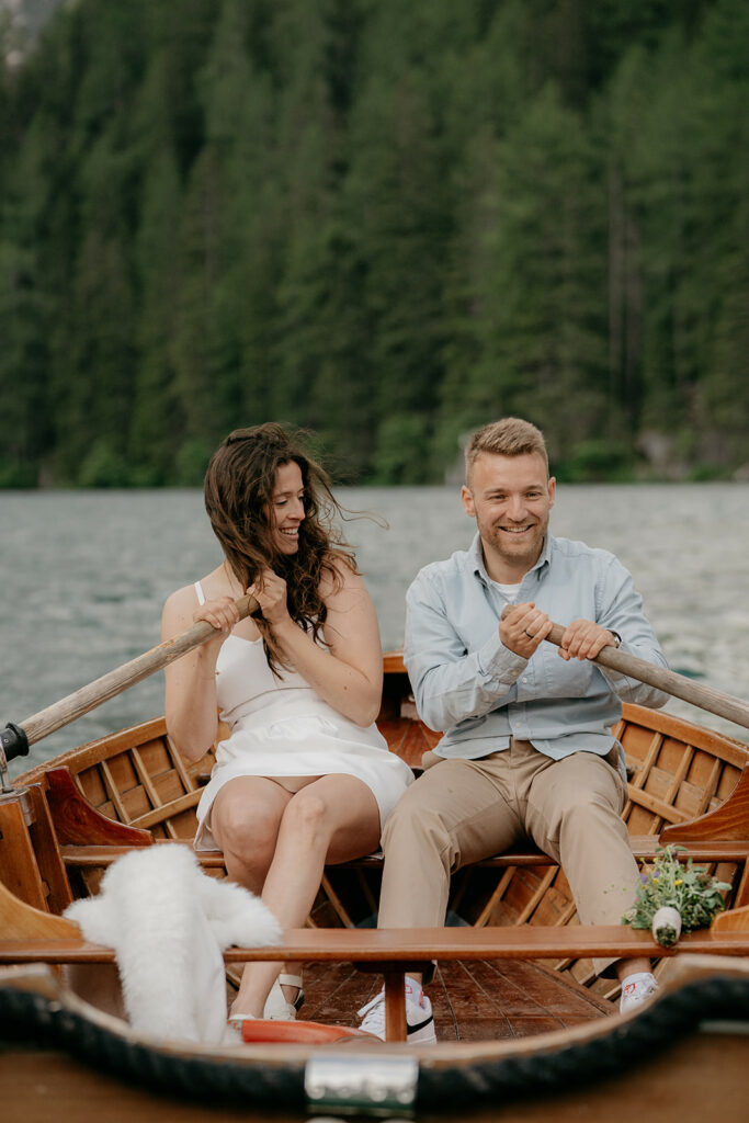 Couple rowing wooden boat on a lake.