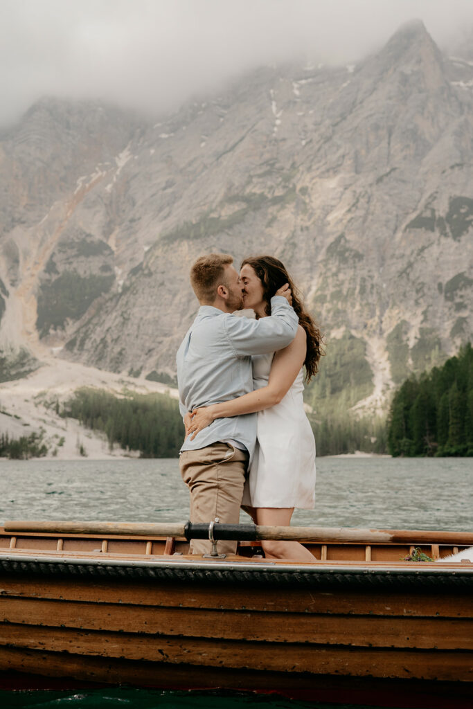 Couple kissing in boat with mountains background.