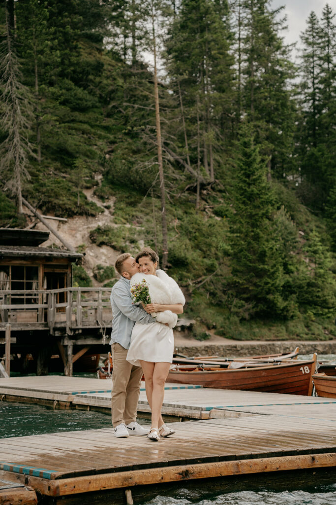 Couple embracing on lakeside wooden dock.