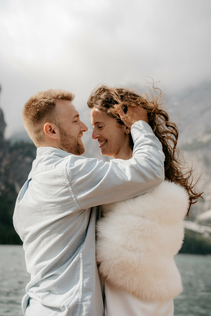 Couple smiling by a scenic lake and mountains.