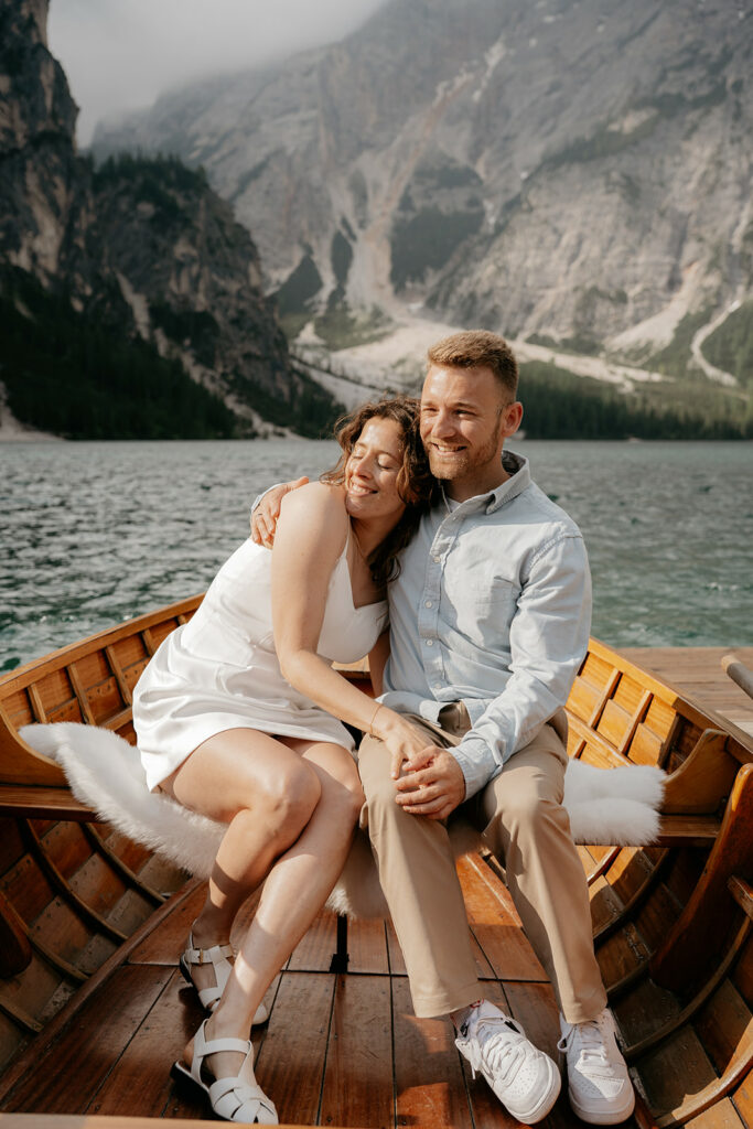 Couple hugging on a boat in scenic mountains