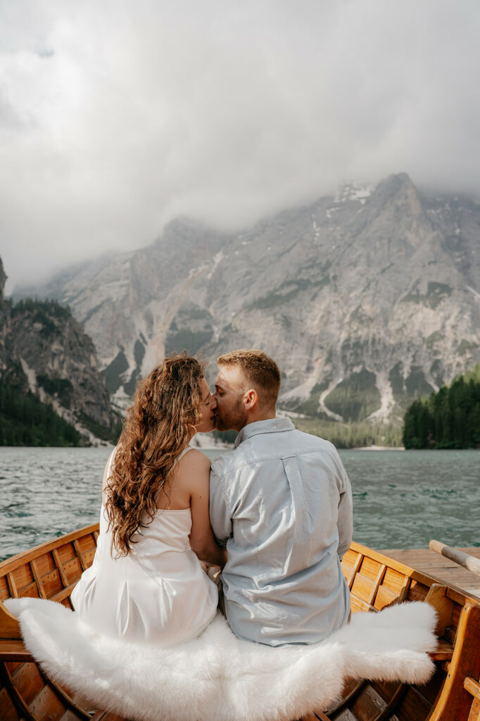 Couple kissing in boat with mountain backdrop