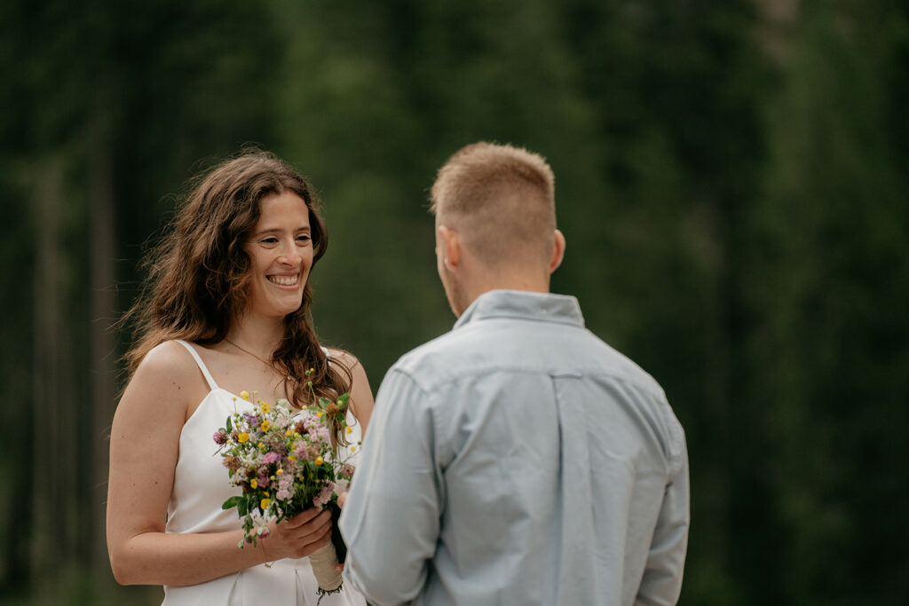 Couple exchanging vows in forest wedding ceremony.