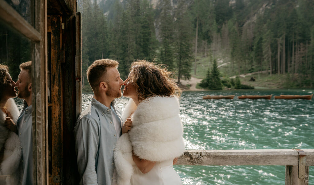 Couple kissing by scenic lake and forest view.