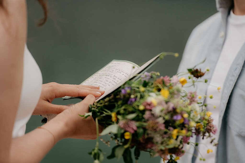Person holding wedding vows and bouquet