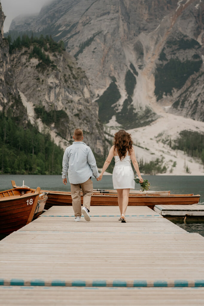 Couple walking on dock with mountain view.