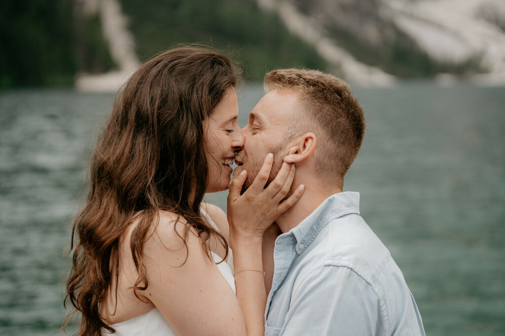 Couple embracing by lakeside with mountains background