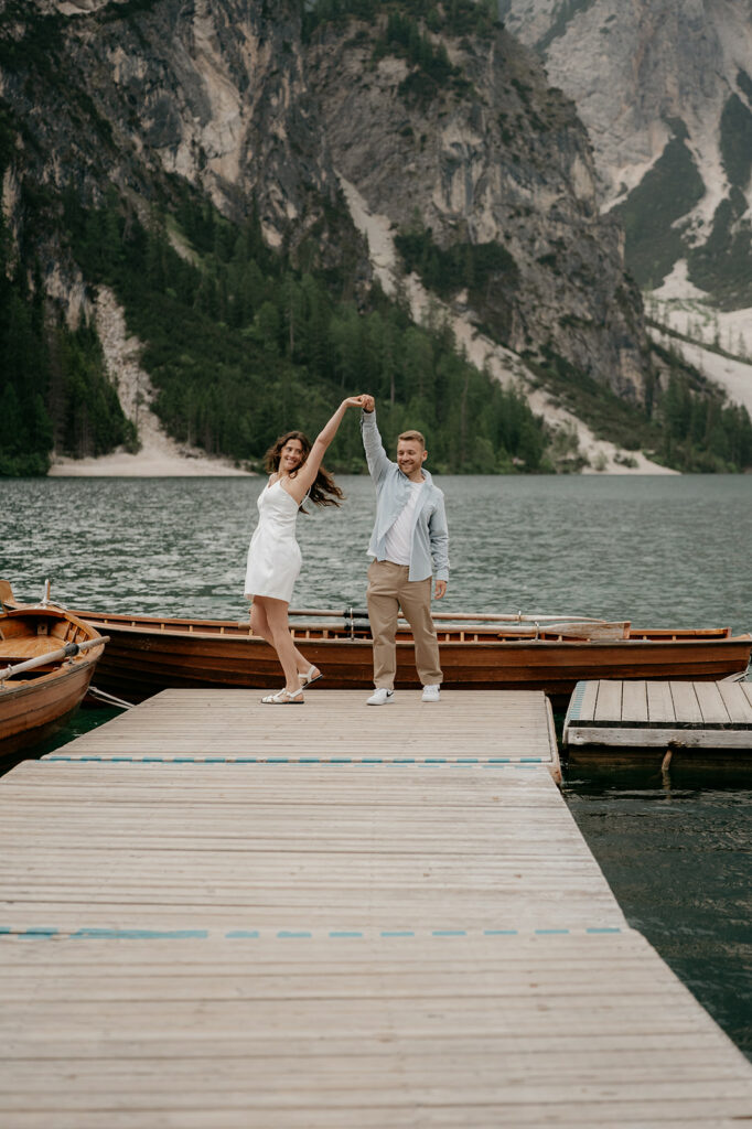 Couple dancing on dock by mountain lake.