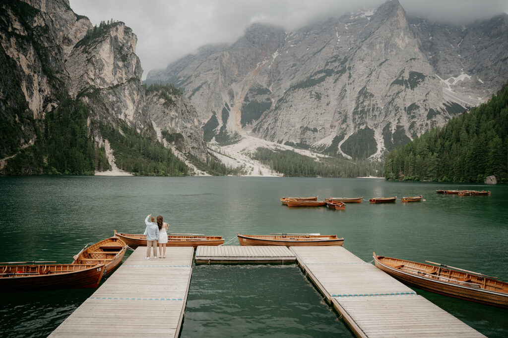 Couple on dock with mountain and boats view.