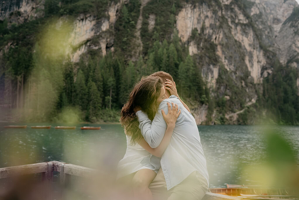 Couple embracing by serene mountain lake.