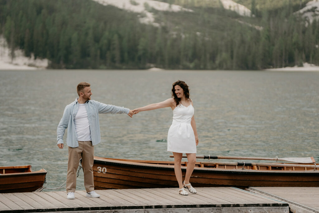 Couple holding hands on lakeside dock.