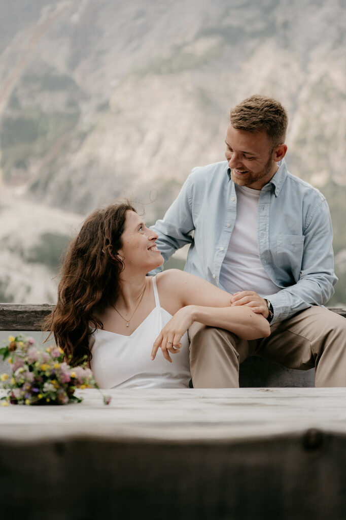 Couple smiling in outdoor mountain setting.