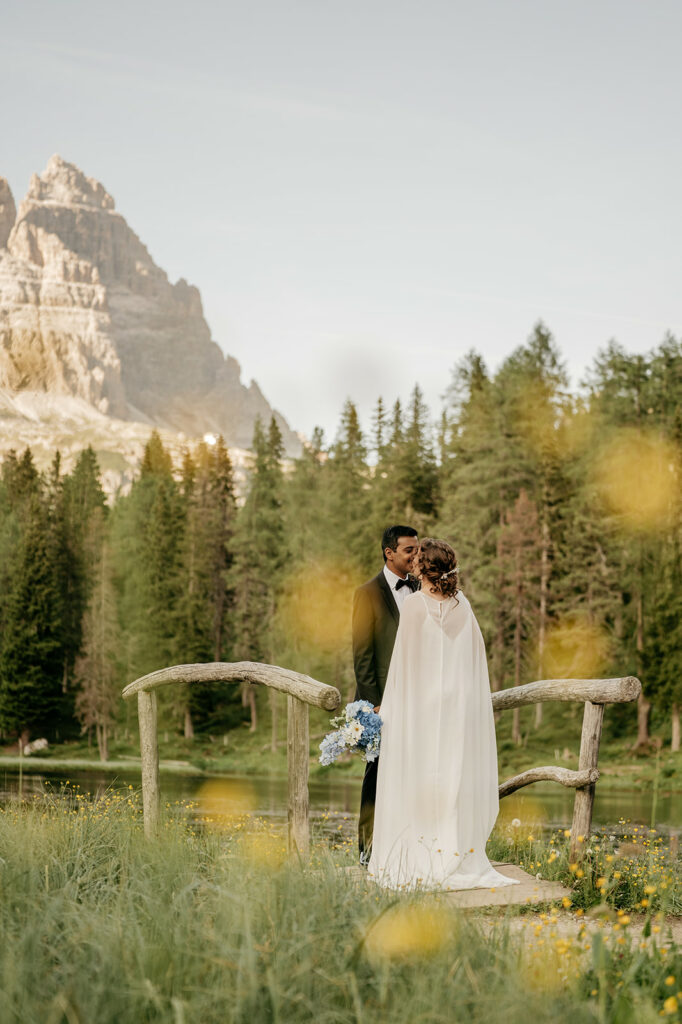 Couple kissing on bridge, mountains in background