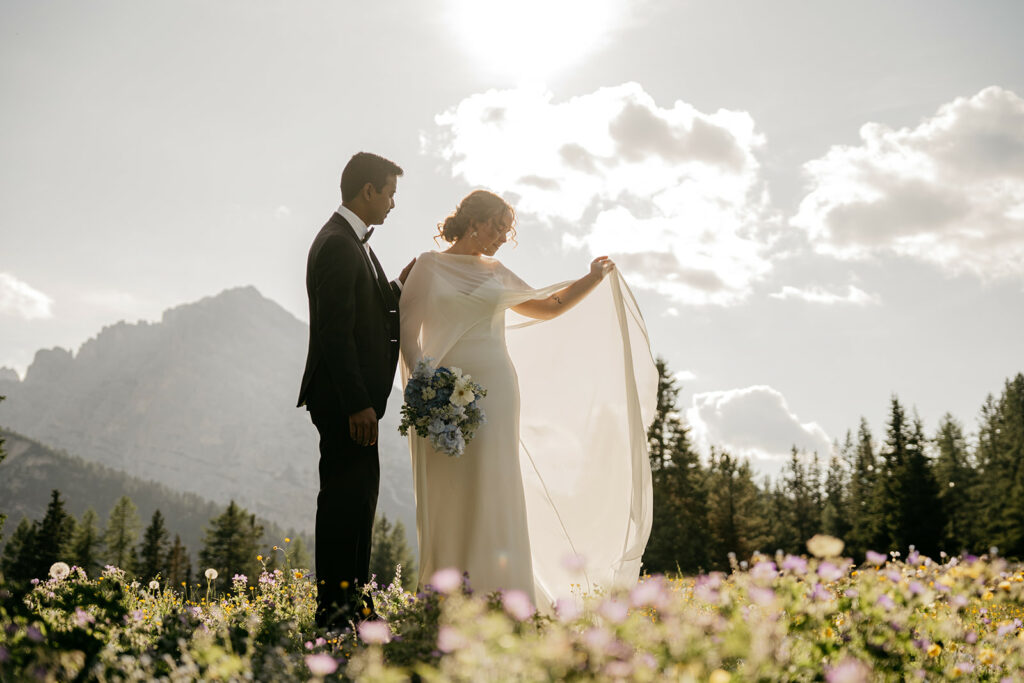Bride and groom in mountain meadow at sunset.