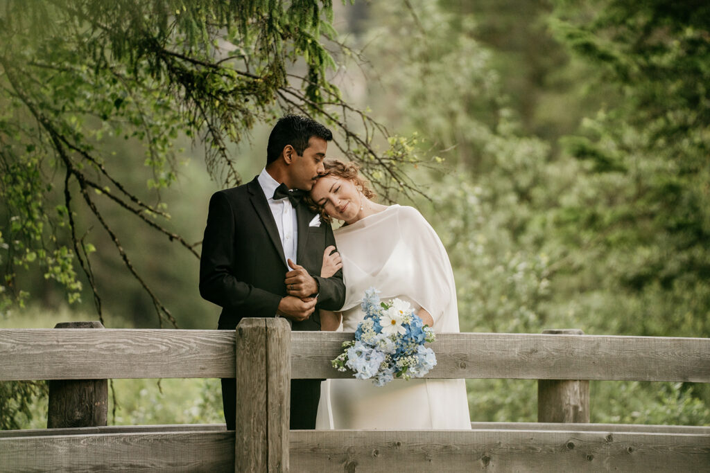 Bride and groom standing on a wooden bridge.