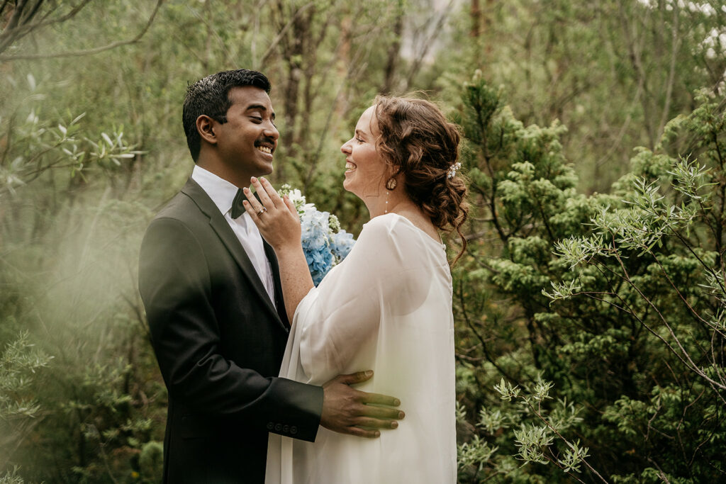 Bride and groom smiling in lush green forest