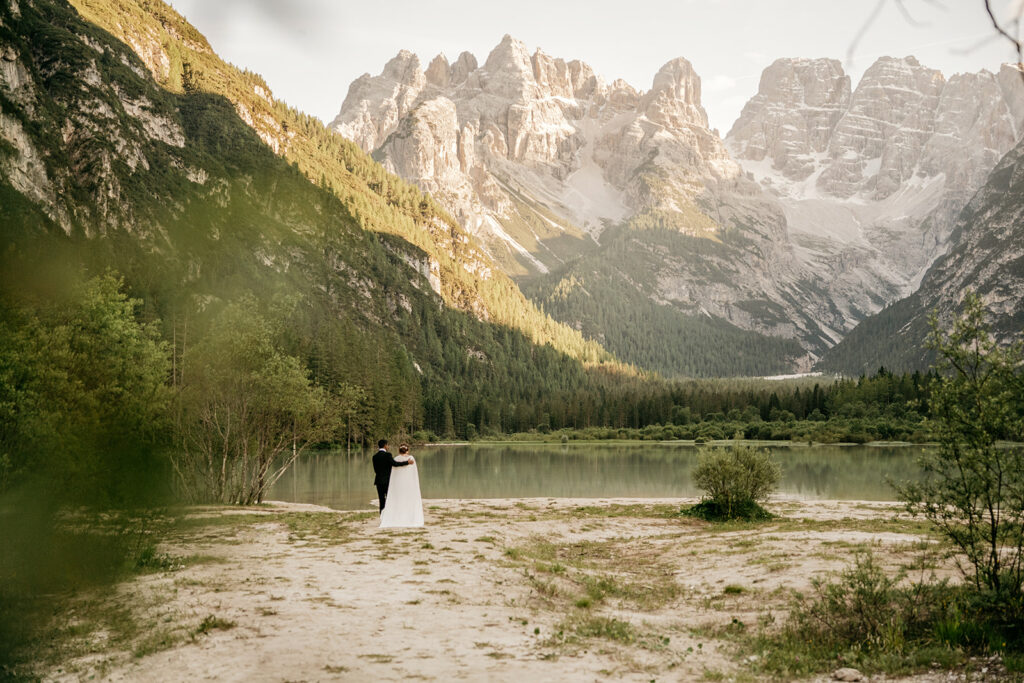 Couple embraced by mountain lake with scenic views.