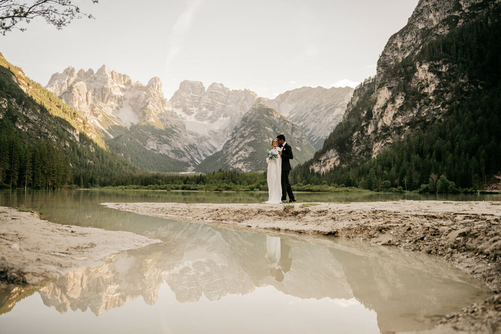 Couple embracing by mountain lake scenery.