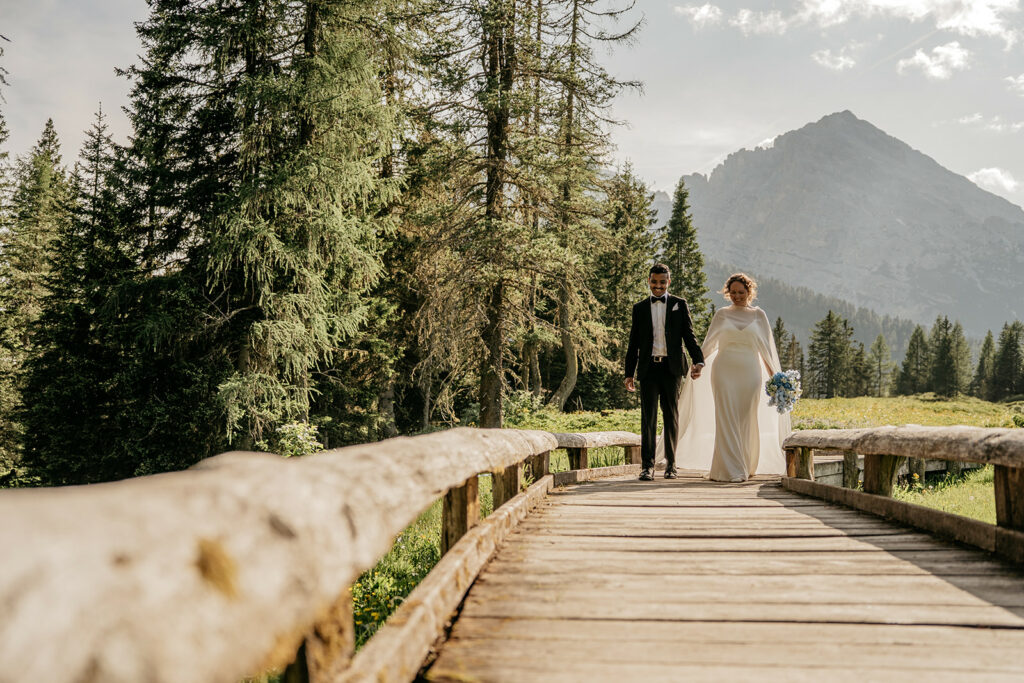 Couple walking on wooden bridge in scenic forest.