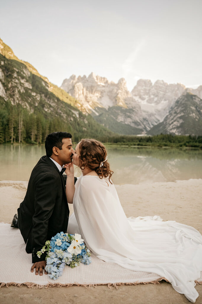 Couple kissing by mountain lake with flowers
