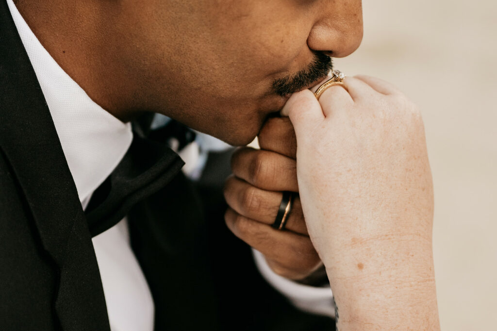 Man kisses hand wearing wedding rings.