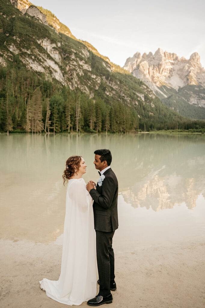 Couple embracing by mountain lake during sunset