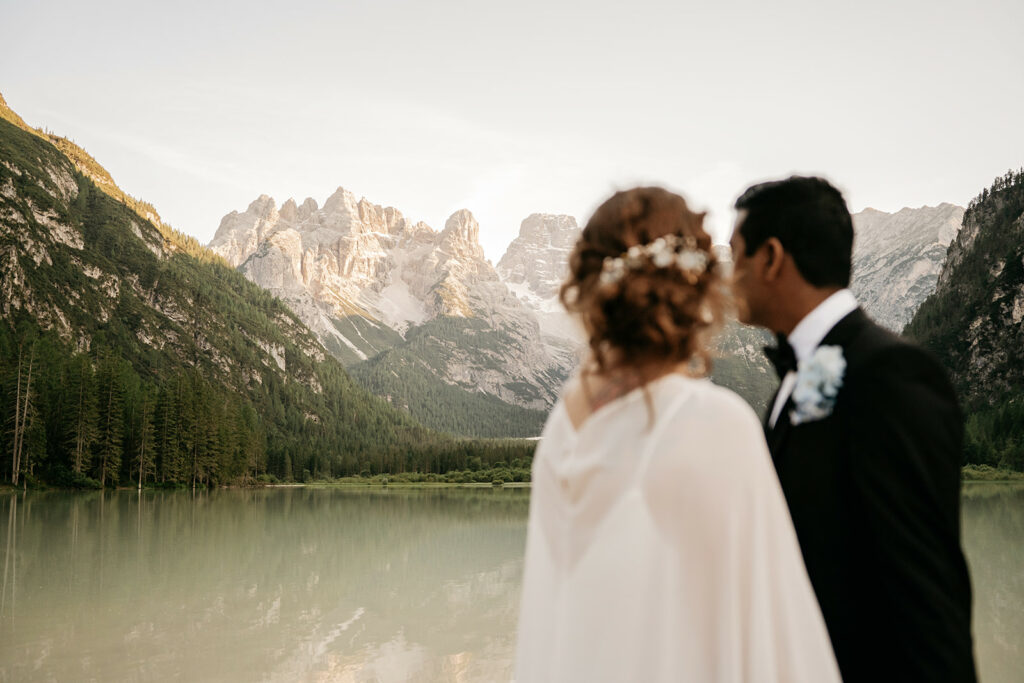 Couple by a serene mountain lake at sunset.