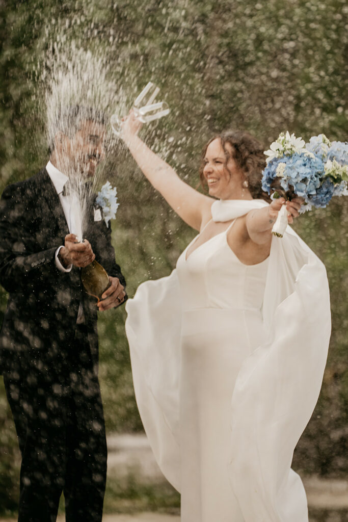 Bride and groom celebrate with champagne spray.