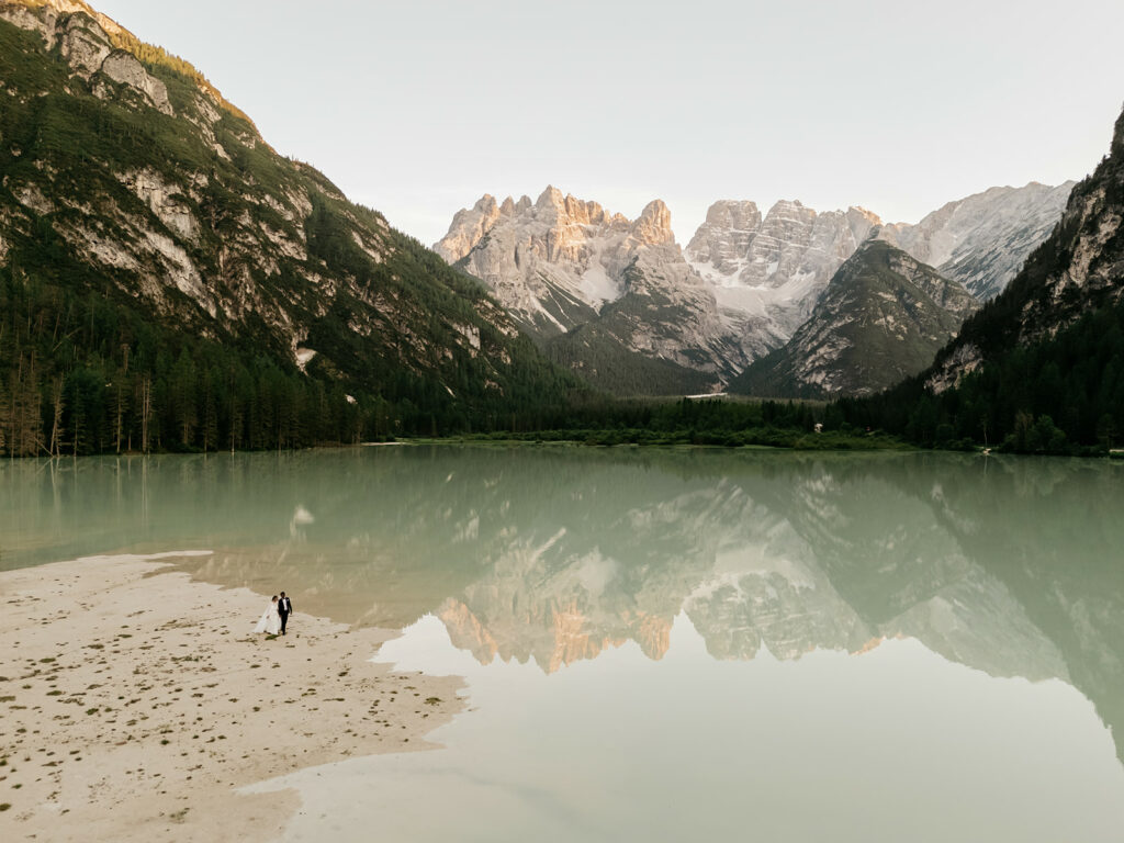 Couple by serene lake with mountain backdrop.