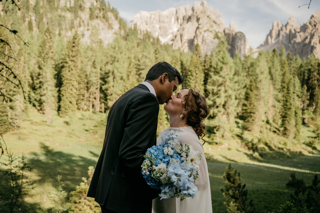 Couple kissing outdoors with mountain background.