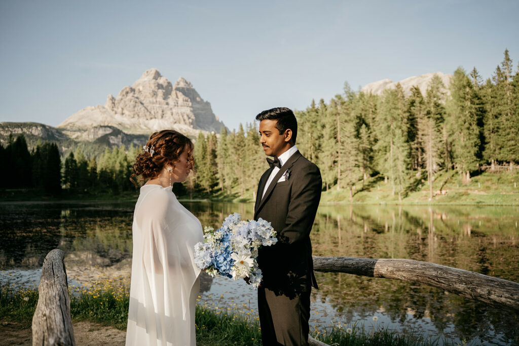 Couple wed by lake with mountainous backdrop.