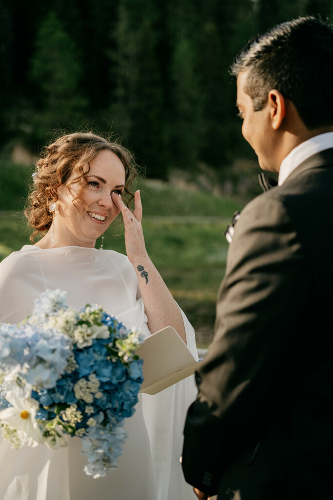 Bride wiping tears during outdoor wedding