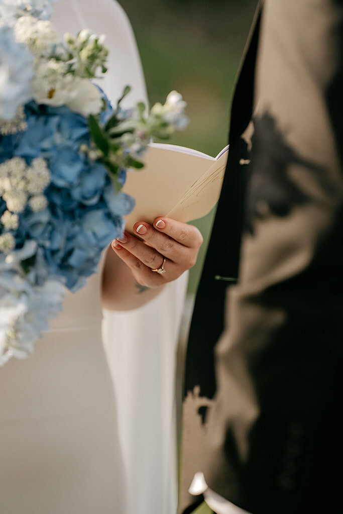 Bride holding bouquet and vows during wedding ceremony.