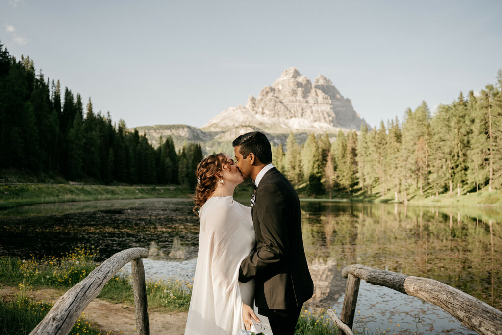 Couple kissing by mountain lake scenery.