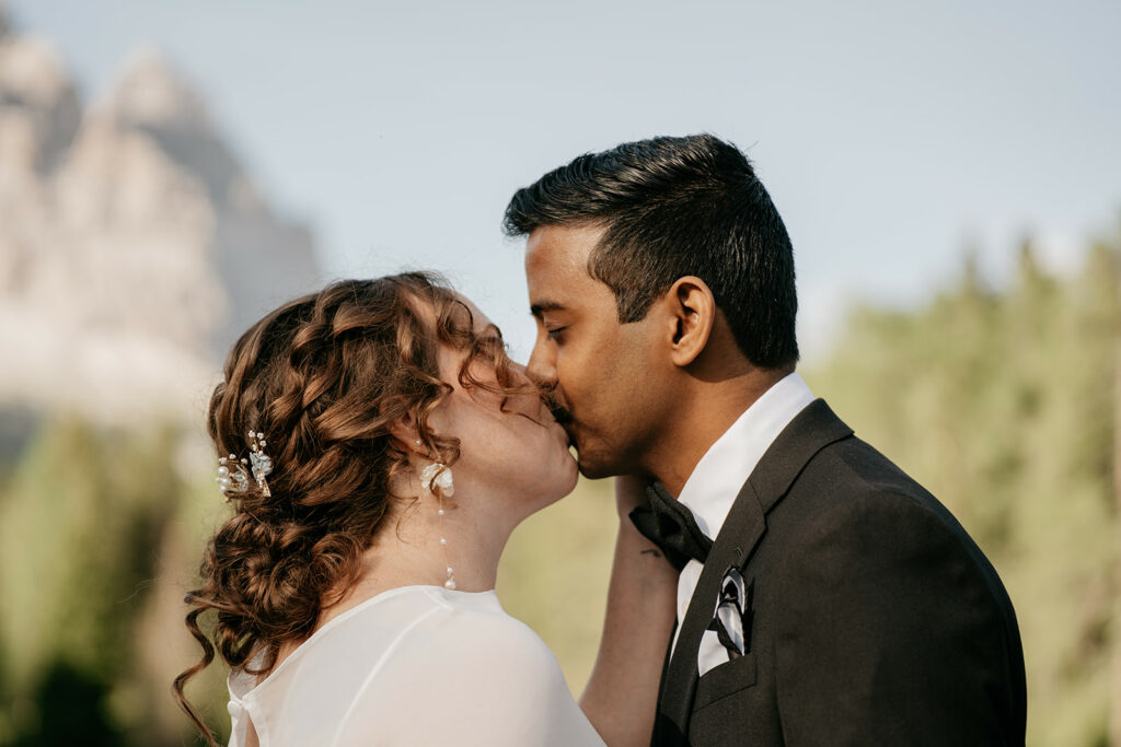 Couple kissing outdoors at wedding ceremony.