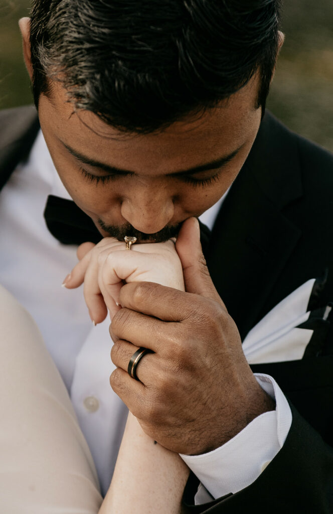 Man kissing partner's hand, showing wedding rings.