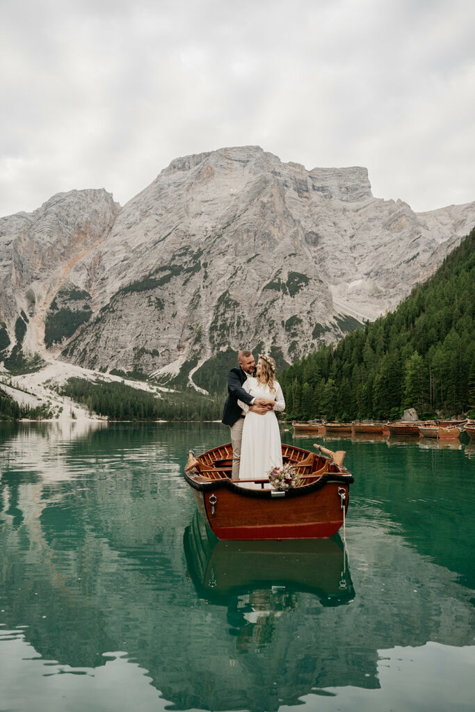 Couple embraces on boat in mountain lake scenery.