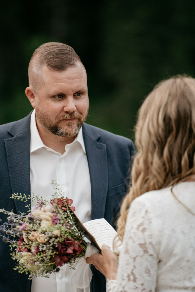 Couple exchanging vows outdoors with bouquet