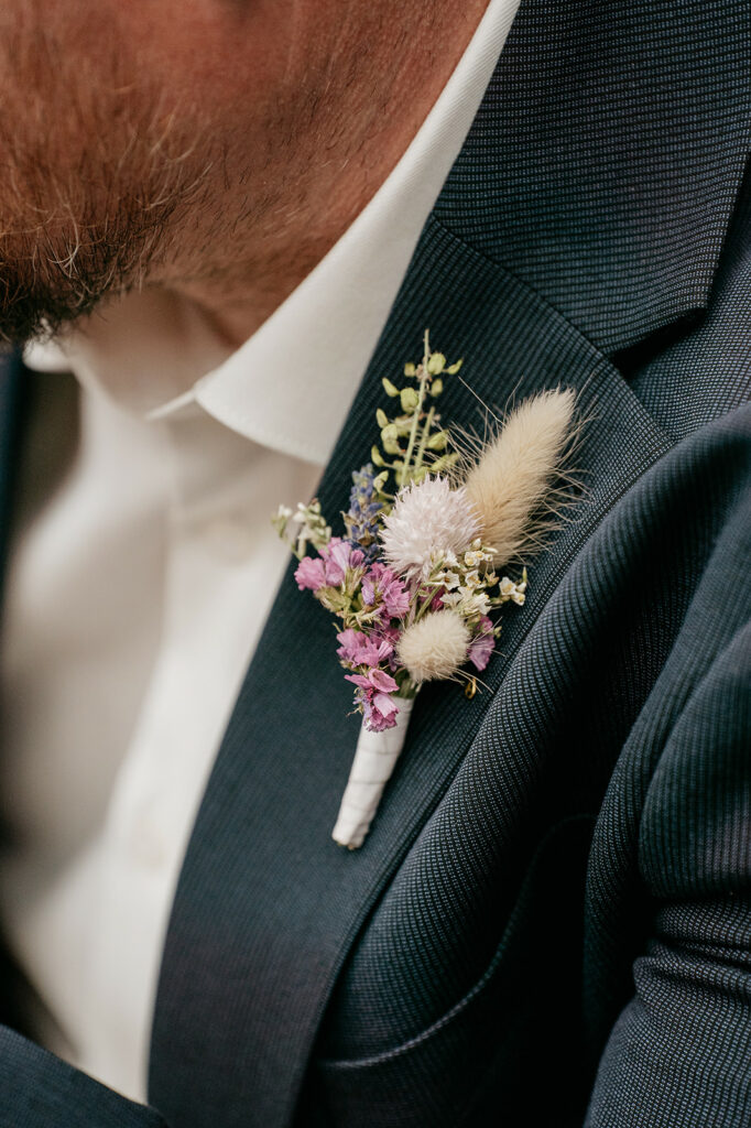 Groom's boutonniere with dried flowers on suit jacket.
